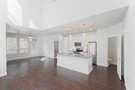 Open living areas with wood inspired flooring throughout, high ceilings, white trim, white walls