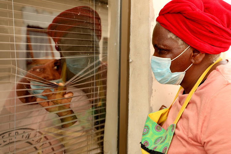 Bongiwe Sofeke, 63, of Kwazakhele, right, shows how she has to speak to her daughter Ncediswa, 32, who has contracted Covid-19 and is in self-isolation in a flat outside the main house. Four members of the family have tested positive