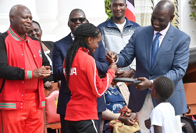 Faith Kipyegon receives the key to her new house in Parkroad from President William Ruto as Athletics Kenya President Lt. Gen (Rtd) Jack Tuwei looks on.