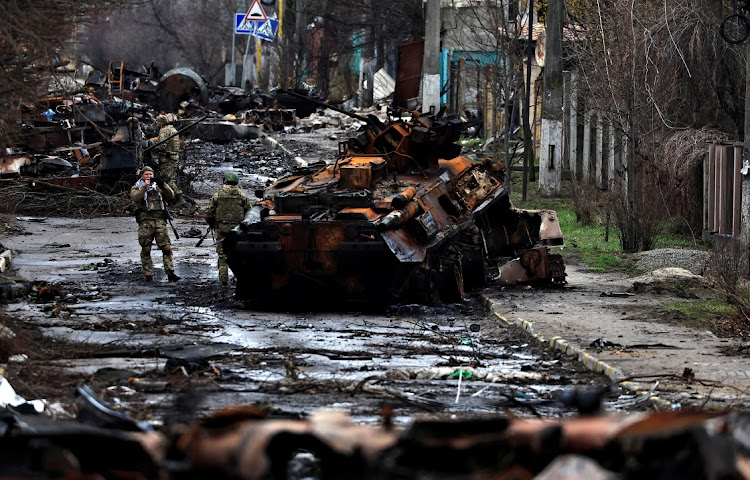 A soldier takes a photograph of his comrade as he poses beside a destroyed Russian tank and armoured vehicles, amid Russia's invasion on Ukraine in Bucha, in Kyiv region, Ukraine on April 2 2022. Picture: REUTERS/ZOHRA BENSEMRA