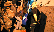 Residents carry a drum full of homemade beer confiscated by the police   in Alexandra during a patrol with troops and community leaders. 