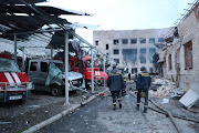 Rescuers walk along of destroyed vehicles at a compound of a fire depot of the State Emergency Service heavily damaged by a Russian missile strike, amid Russia's attack on Ukraine, in Dnipro, Ukraine May 22, 2023. 