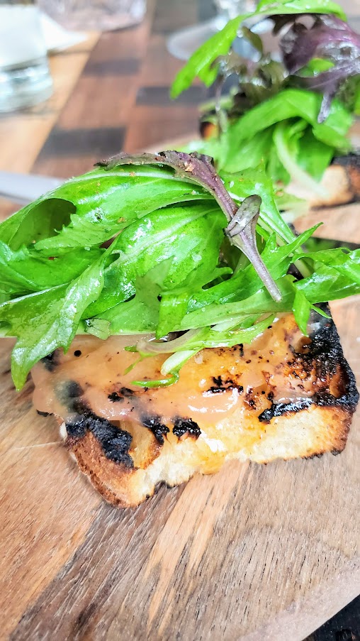 Tiny Toast, a grilled levain bread with Uni Butter, Rhubarb Jam, Szechuan, and Arugula available at dinner and happy hour at Normandie PDX