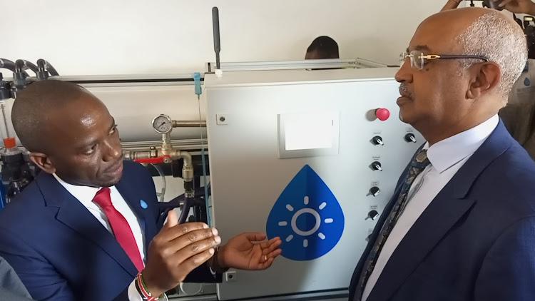 WaterKiosk Managing Director Samuel Kinyanjui explains to health CAS Dr Rashid Aman how the solar water desalination plant installed at the Kibera Level 3 hospital works, on October 13, 2022