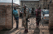 A member of the SANDF offers hand sanitiser to residents while patrolling the streets of Soweto to enforce lockdown regulations. During the patrol they checked permits and made several arrests and confiscated goods. 