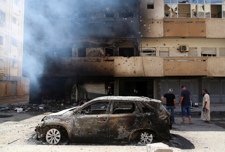 Men look at a burning building after deadly clashes in Tripoli, Libya. August 28 2022. Picture: HAZEM AHMED/REUTERS