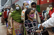 Passengers wait in line to get their temperature checked at a railway station amid the spread of the coronavirus in Mumbai, India on November 26, 2020. 