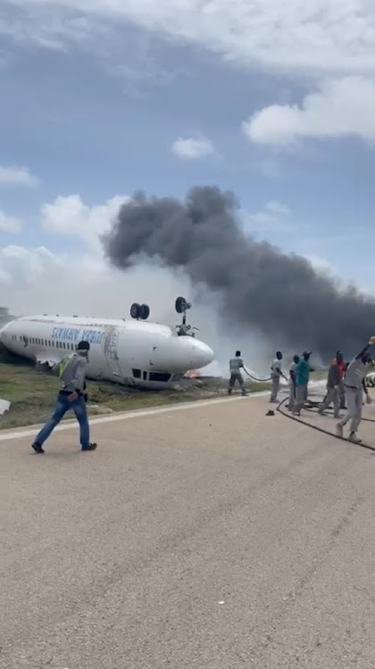 Firefighters spray water on a plane that flipped over after a crash landing, in Mogadishu, Somalia, July 18, 2022, in this screen grab obtained from a social media video obtained by Reuters.