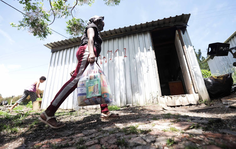 Mauritia Oktober, a resident of Wilderness Heights informal settlement walks back to her home after receiving aid from the Gift of the Givers.