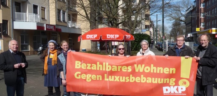 Genossinnen und Genossen am DKP-Schirm. Transparent: «Bezahlbares Wohnen! Gegen Luxusbebauung! DKP».