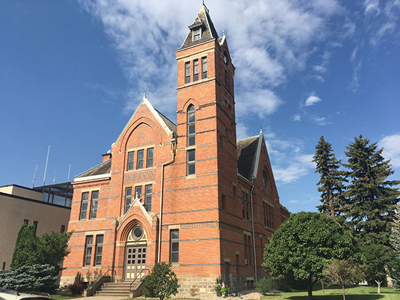 Outside of the Stutsman Courthouse building a red brick building with a blue sky behind