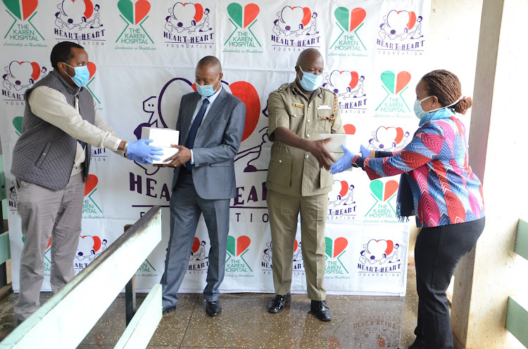 Heart to Heart Foundation director Joe Nyaga and Karen Hospital CEO Juliet Nyaga (on the edges) donate face masks and gloves to Langata chief inspector Riziki Ali and OCPD Gregory Mutiso (C)