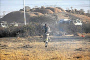 File photo of a mineworker running away from police armoured vehicles. He was among thousands of Marikana miners who had gathered  to protest for a pay increase. 