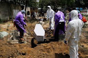 Relatives lower the body of a person who died from coronavirus into a grave, at a graveyard in New Delhi, India, on April 29 2021. 