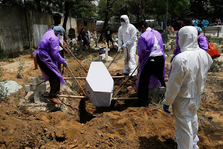 Relatives lower the body of a person who died from coronavirus into a grave, at a graveyard in New Delhi, India, on April 29 2021.