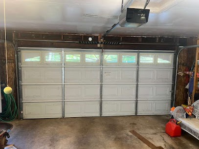 Interior view of a wide white residential garage door with a top row of windows, overhead motor unit, and heavy-duty torsion springs installed in Crofton.