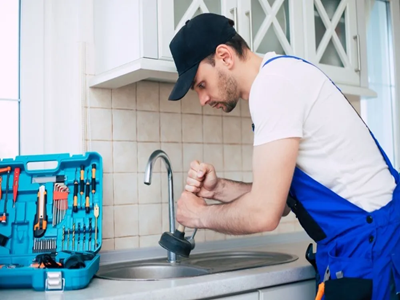Professional plumber fixing a kitchen sink leak and clogged drain