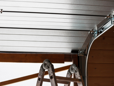 Close-up interior view of an aluminum sectional overhead garage door tracking smoothly along the curved rail during a professional maintenance service in  Crofton