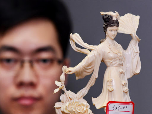 STOPPED: A police officer demonstrates a curved ivory statue in China last year.