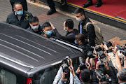 Stand News Editor-in-Chief Patrick Lam is brought into a vehicle after police searched the offices of the independent news outlet on December 29, 2021 in Hong Kong, China. Editors, board members and a pop singer were arrested in the early morning sweep as 200 officers raided the office. 