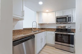 Modern kitchen in an apartment with stainless steel appliances, white cabinetry, and granite countertops.