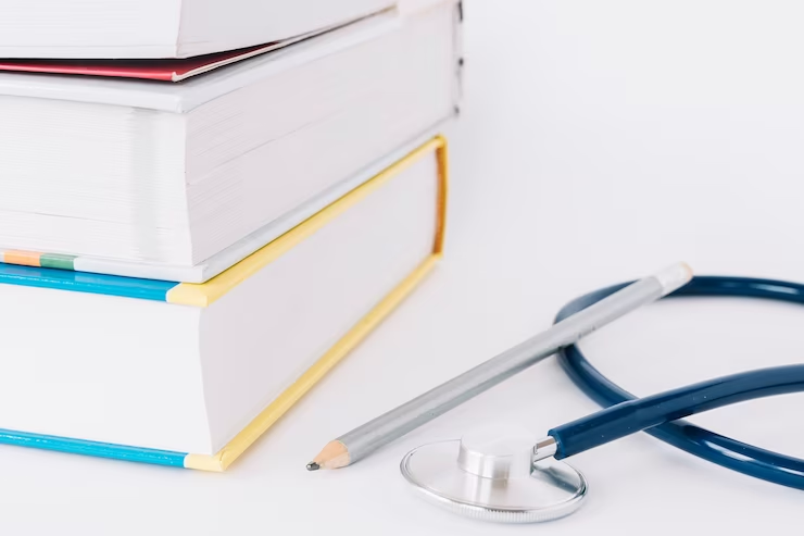 Books, pencil, and stethoscope on a white surface