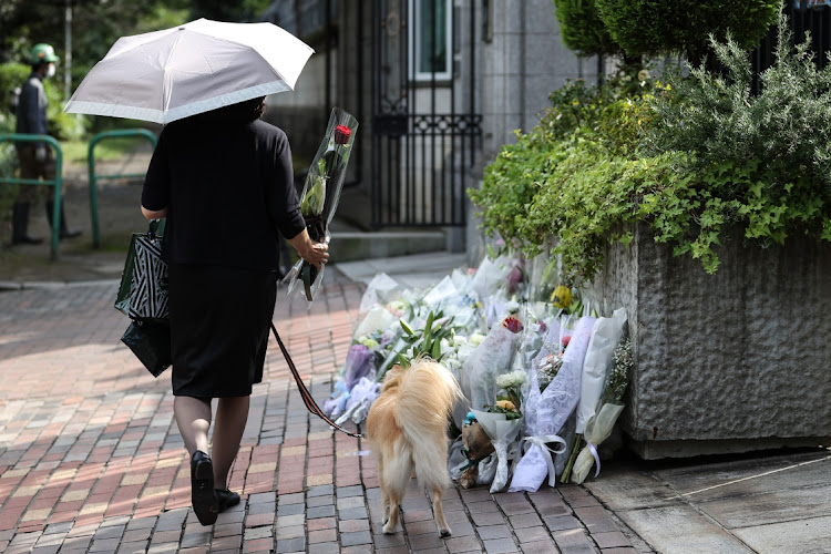 A woman lays flowers in front of the British embassy in Tokyo on September 8 2022 after Queen Elizabeth II died at the age of 96.