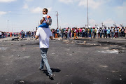 A man walks with a child on his back near the protesters.