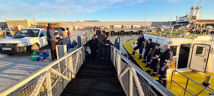Crew of the National Sea Rescue Institute's Spirit of Vodacom deliver groceries to Robben Island residents on April 8 2020.