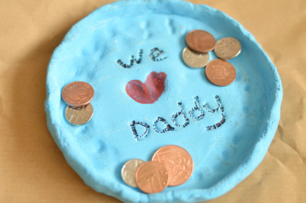 A light blue fingerprint plate with a red fingerprint heart in the center. Coins are placed on the plate.