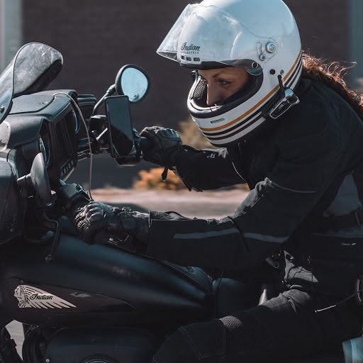 Mulher de capacete andando de moto.