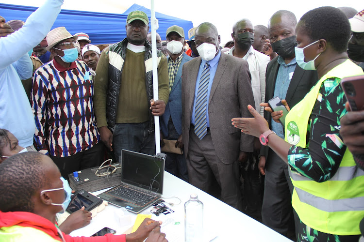 Former Kasipul MP Oyugi Magwanga and Lake Basin Development Authority chairman Odoyo Owidi monitor the ongoing IEBC mass voter registration at Kosele in Kasipul constituency on January 17.