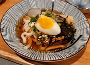 Cold Japanese udon noodles served in a broth and topped with spring onion, nori, bamboo shoots and sesame seeds.