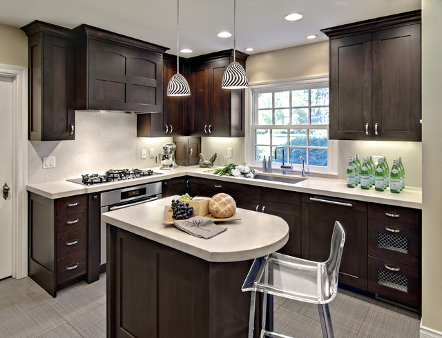 dark espresso shaker cabinets bring contrast to this small l-shaped kitchen. under cabinet lighting illuminates the space, while a simple white backsplash and grey floors brighten up the color palette 