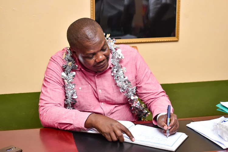 MP Jack Wamboka signing a visitors book at St. Mary's Mukhuma scondary school.