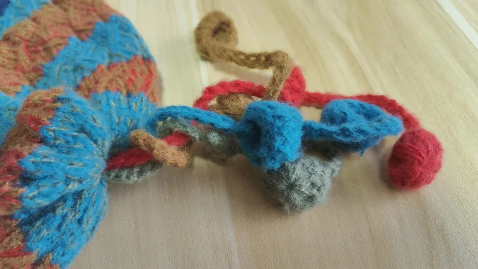 Bonnet d'hiver saisonnier en laine crocheté à la main avec des boules colorées et une sangle, chaud, confortable et tendance.