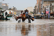 Residents make their way through a flooded street after heavy rains in Yoff, district of Dakar, Senegal July 20, 2022. 