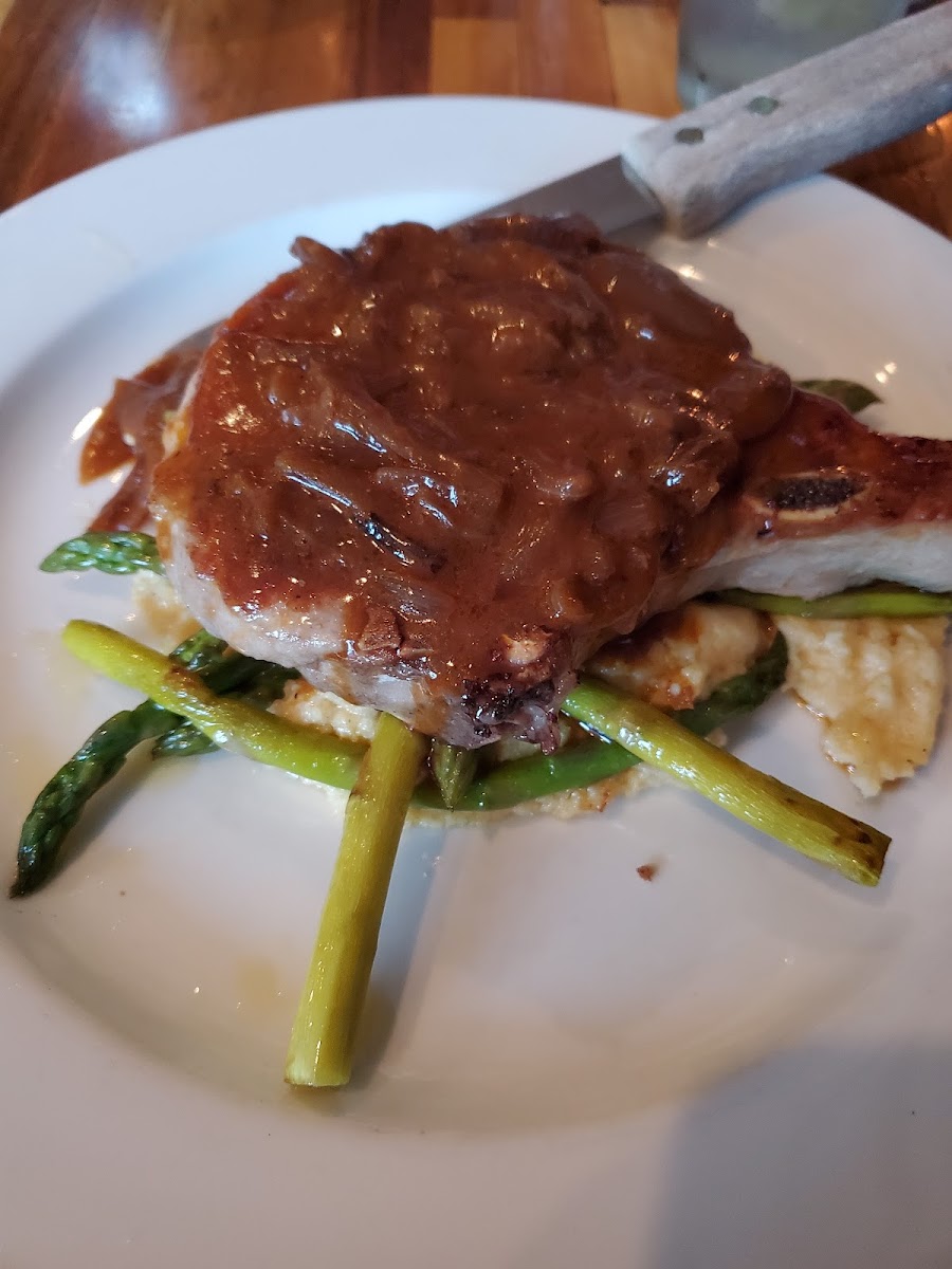 Pork chop served over polenta and asparagus, topped with onion demi.
