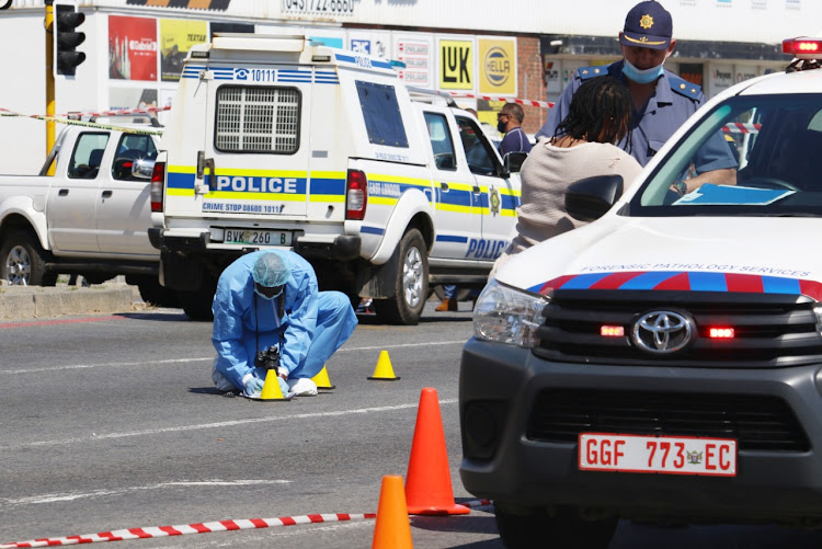 Police and forensics team members at the scene of a police shootout in East London that left one suspected armed robber dead and another fighting for his life.