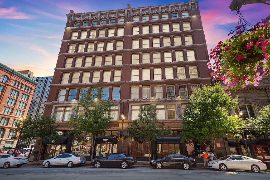 Brick historic apartment building downtown at dusk with flowerpot in front view and trees lining sidewalk