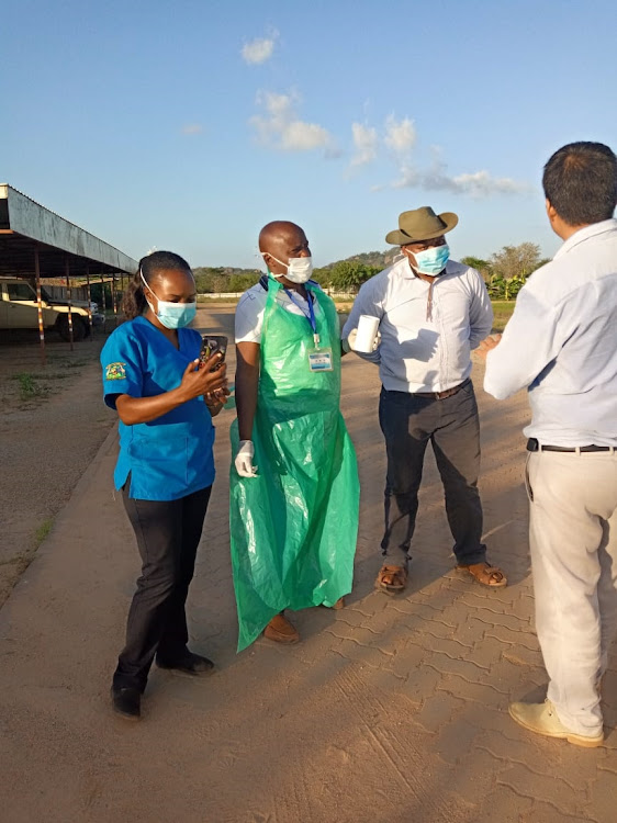 Masked medical personnel speak to a Sino-Hydro Corporation worker at the Mutomo campsite on Monday. They were denied access to the isolated worker.