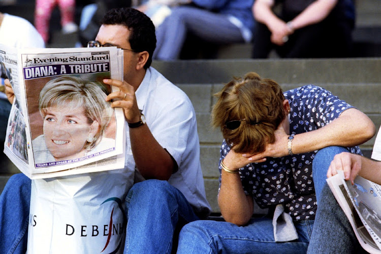 A man reads a paper paying tribute to Diana, Princess of Wales, as a grief-stricken woman covers her face on the steps of Saint Paul's cathedral in London.