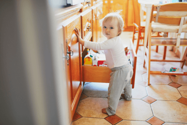 Toddler standing next to an open kitchen drawer