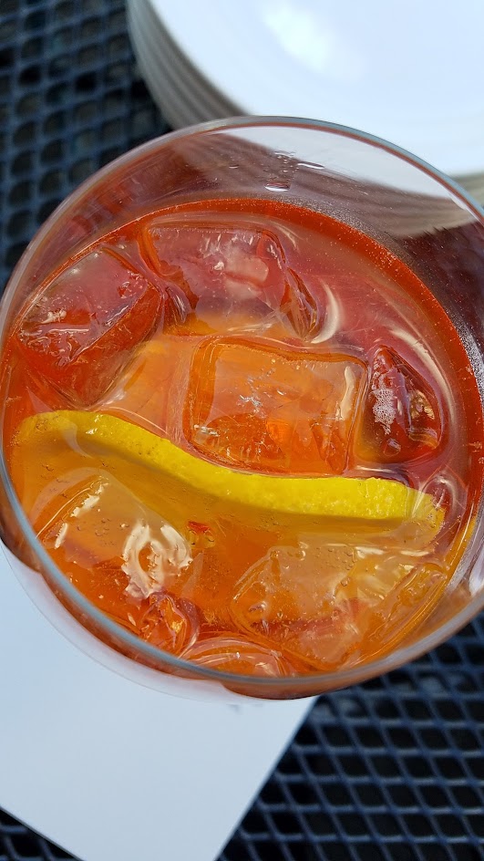 Aperol Spritz with Aperol, Sparkling Wine, and orange wheel, one of six curated cocktails offered at Ken's Artisan Pizza