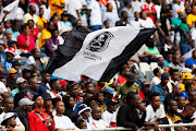 Orlando Pirates supporters wave the club's flag during a DStv Premiership match against TS Galaxy at Mbombela Stadium on April 30 2023.