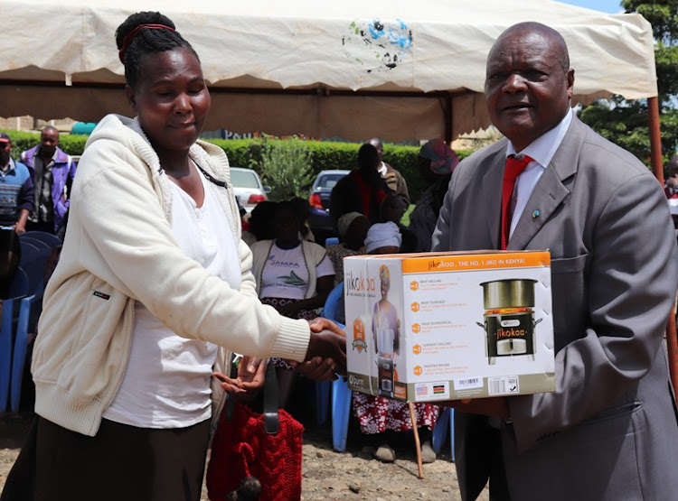 A Mungania tea farmer receives a smoke-free jiko from Embu KTDA chairman Julius Nyagah on Wednesday