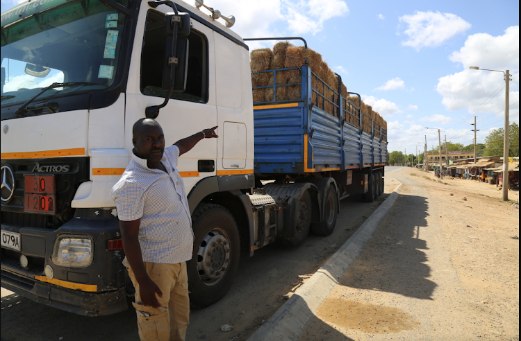 Charles Njenga stands beside his lorry full of 3,000 bales of hay in Hindi Town, Lamu which he intends to sell to herders in Lamu whose livestock have been stricken by drought.