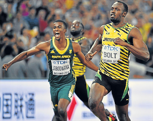 SA’S BOLT OF LIGHTNING: Usain Bolt, right, of Jamaica celebrates after winning the gold medal in the men’s 200m final during the World Championships at the National Stadium, also known as Bird’s Nest, in Beijing yesterday. South Africa’s Anaso Jobodwana, left, won third place in 19.87 seconds Picture: EPA