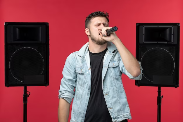 The guy sings with a microphone on the background of music speakers