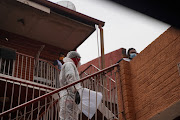 Paramedic Clive Moeleso escorts a suspected Covid-19 patient from his home to an ambulance in Lenasia. 